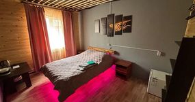 Номер 4 комната 1: двуспальная кровать, прикроватная тумба, полка для одежды, маленький холодильник, лицевые полотенца (апрель 2026).